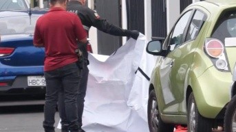 Foto de un policía tendiendo una sábana blanca sobre el cuerpo de una adolescente asesinada en Manta, el 3 de septiembre. (Televistazo)