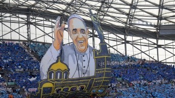 Aficionados del Olympique de Marsella con una enorme pancarta del Papa Francisco a su llegada para celebrar la misa en el estadio Velódromo, el 23 de septiembre de 2023. (AFP)