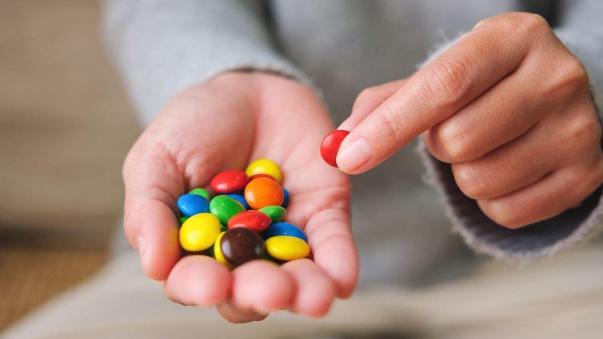 Hombre con chocolates de colores en su mano. (Foto: Internet)