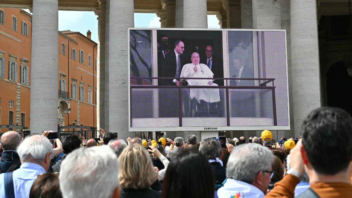 La gente observa pantallas gigantes que muestran al Papa Francisco apareciendo en un balcón del hospital Gemelli el día de su alta tras cinco semanas de hospitalización. (Foto: AFP)