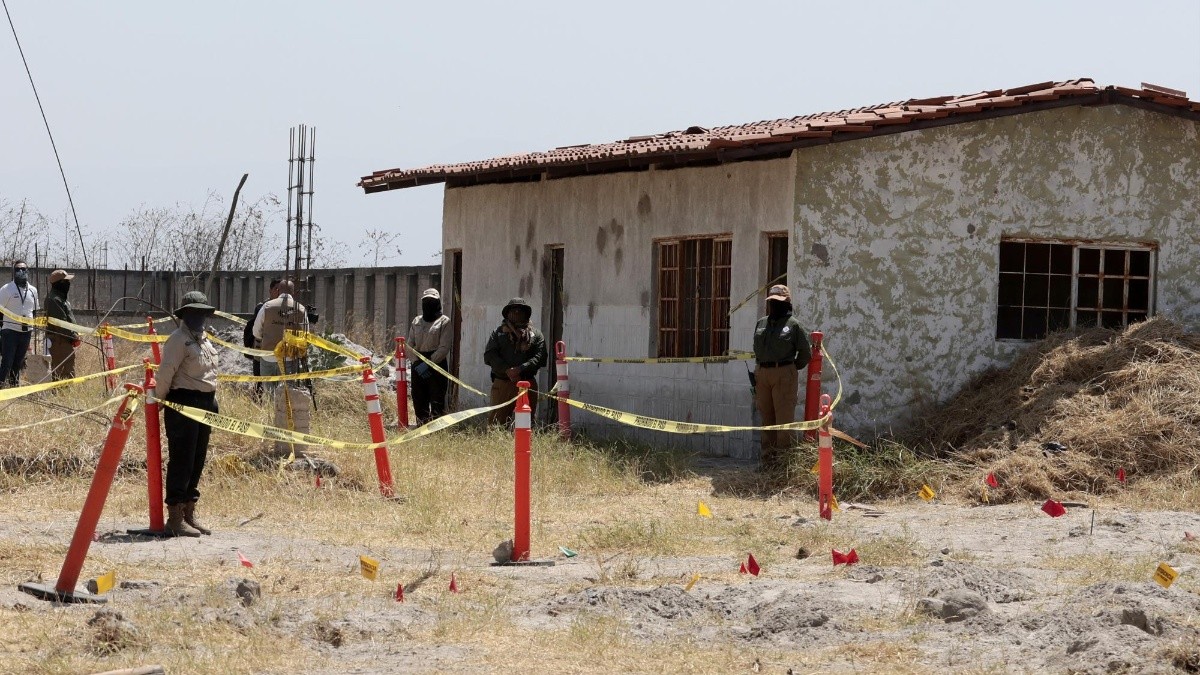 Los miembros de la Comisión Nacional de Búsqueda (CNB) se encuentran detrás de un área acordonada en el "Rancho Izaguirre" durante un recorrido con medios de comunicación en Tehuchitlán. (AFP)