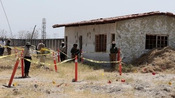Los miembros de la Comisión Nacional de Búsqueda (CNB) se encuentran detrás de un área acordonada en el "Rancho Izaguirre" durante un recorrido con medios de comunicación en Tehuchitlán. (AFP)