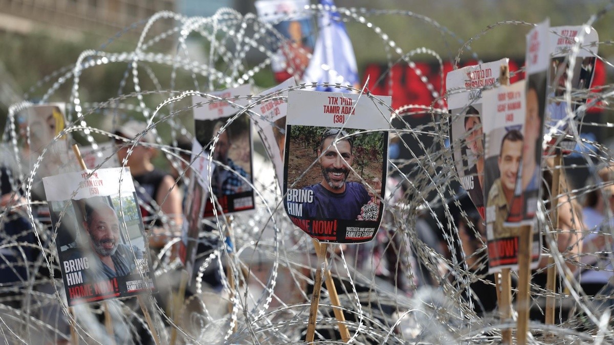 Fotografías de rehenes israelíes retenidos por Hamás en Gaza, colocados sobre una valla de alambre de púas, durante una manifestación de familiares y simpatizantes que exigían un alto el fuego y un acuerdo para la liberación de los rehenes. (ABIR SULTAN / EFE)
