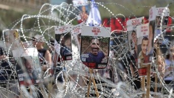 Fotografías de rehenes israelíes retenidos por Hamás en Gaza, colocados sobre una valla de alambre de púas, durante una manifestación de familiares y simpatizantes que exigían un alto el fuego y un acuerdo para la liberación de los rehenes. (ABIR SULTAN / EFE)