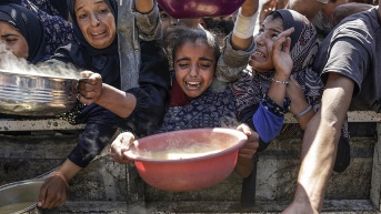 Palestinos desplazados internamente, incluidos niños, sostienen ollas para recibir alimentos de una cocina de caridad, en la ciudad de Gaza. (EFE)