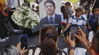 Personas toman fotografías a una imágen del fallecido senador y precandidato de Colombia Miguel Uribe Turbay, durante un homenaje. (Mauricio Dueñas Castañeda / EFE)