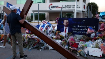 Un hombre carga una gran cruz cerca de un monumento improvisado en honor a Charlie Kirk, fundador de Turning Point USA, frente a la sede de Turning Point USA en Phoenix, Arizona, el 12 de septiembre de 2025. (Foto: AFP)
