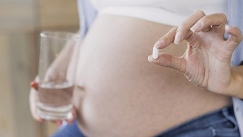 Mujer embarazada con una pastilla. (Freepick)