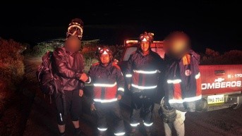 Los bomberos junto a los dos ciclistas rescatados. (Cortesía del CBQ)