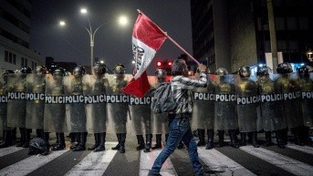 Una persona sostiene una bandera de Perú frente a integrantes de la Policía de Perú durante una manifestación este miércoles, en Lima (Perú). (EFE)
