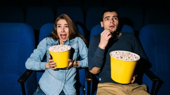 Cinema day, young couple with popcorn looking horror movie in cinema at their date. (Freepik)