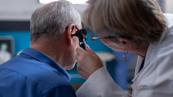 Una doctora utiliza un otoscopio para realizar una consulta de oído a un anciano durante su cita médica. (Freepik)