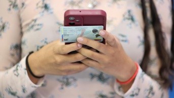 Una mujer con su celular y su cédula durante el simulacro de la consulta popular 2025. (Flickr CNE)