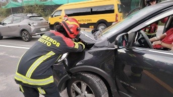 Un efectivo de los Bomberos de Quito junto a un vehículo siniestrado hoy. (Cortesía del CBQ)