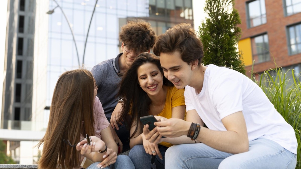 Amigos al aire libre en la ciudad mirando smartphone (Freepik)
