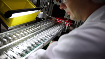 Imagen de un empleado trabajando en una línea de producción de vacunas contra la influenza. (Charly Tribellau/AFP)