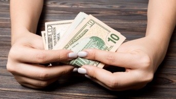 Imagen referencial para graficar a una mujer recibiendo dinero. (Envato)