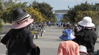 Foto de archivo, personas con gorros protegiéndose de los rayos UV.