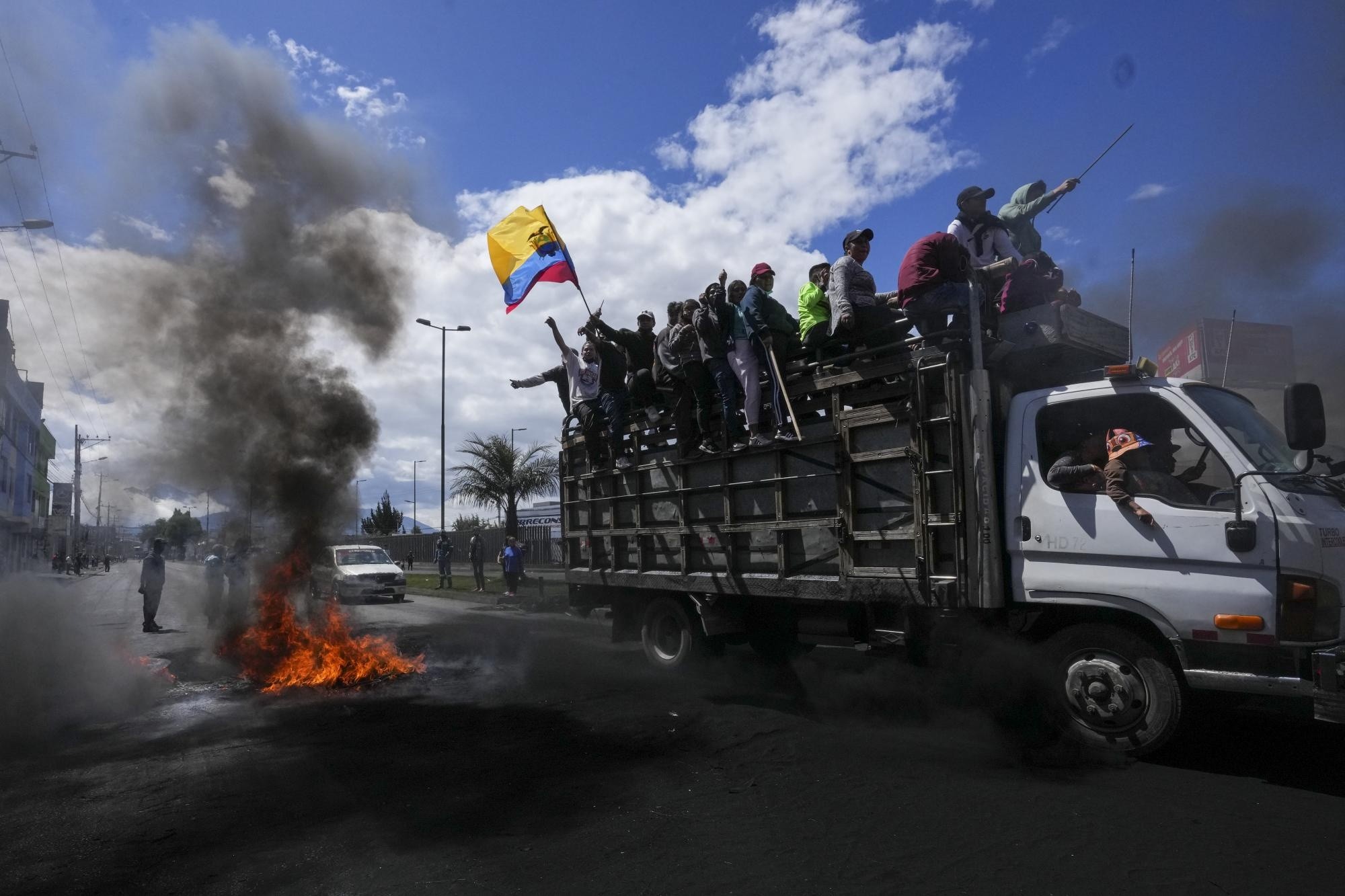 Manifestantes antigubernamentales pasan frente a una barricada en llamas durante protestas contra el gobierno del presidente Guillermo Lasso. (Dolores Ochoa / AP)