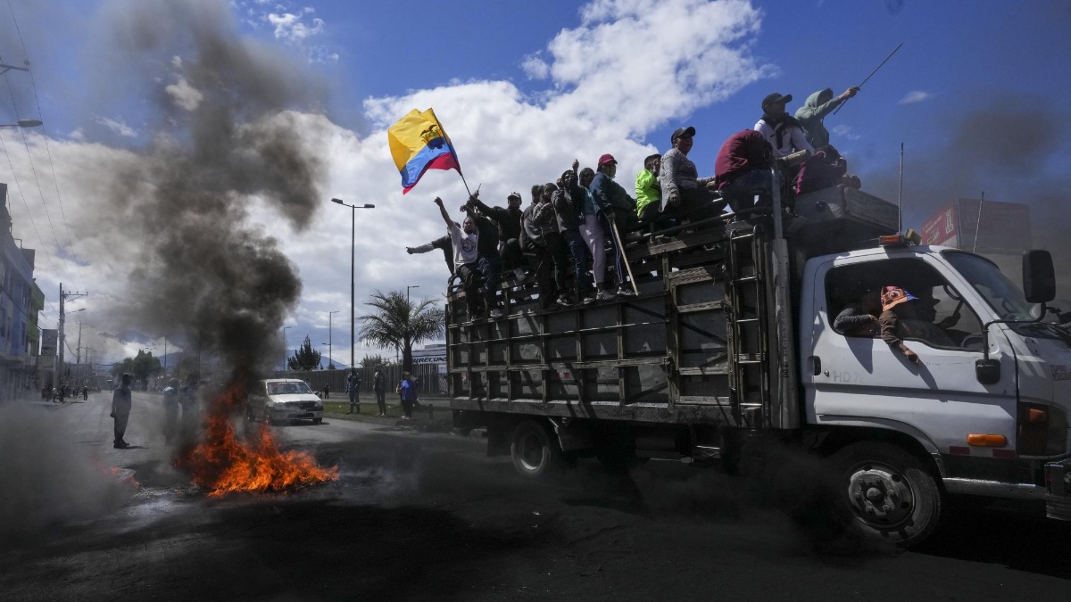 Manifestantes antigubernamentales pasan frente a una barricada en llamas durante protestas contra el gobierno del presidente Guillermo Lasso. (Dolores Ochoa / AP)