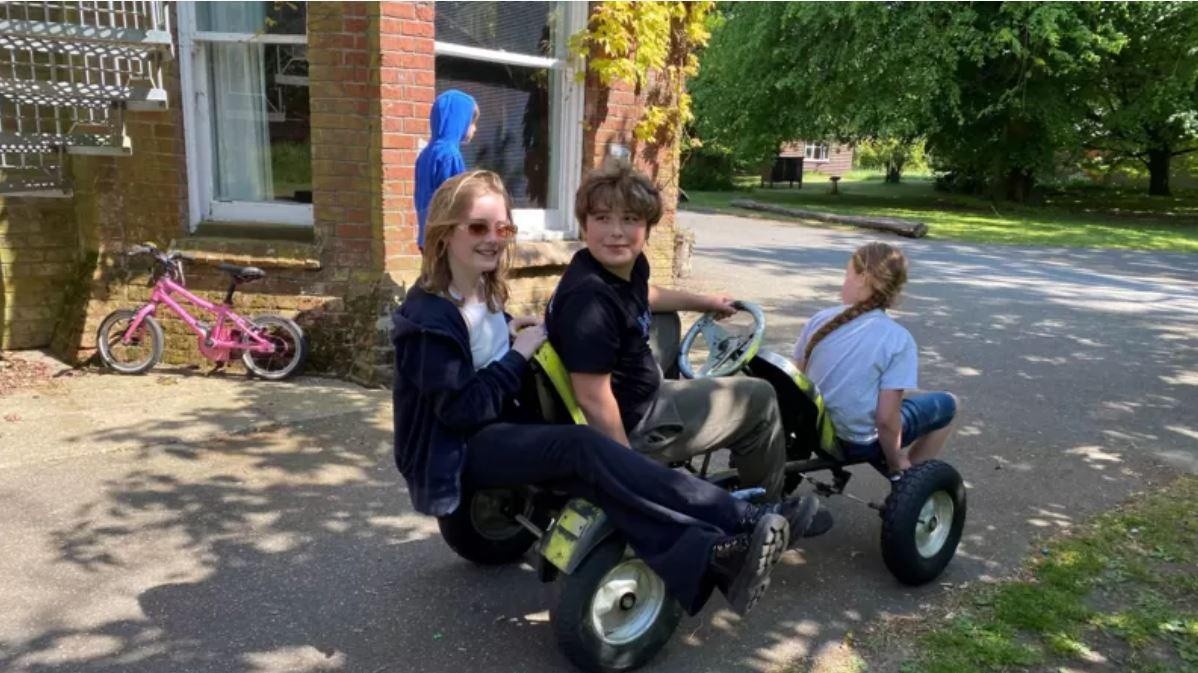 "Básicamente, somos los niños los que dirigimos el colegio", aseguran, de izquierda a derecha, Alba (9), Oscar (11) y Aria (10). (BBC)