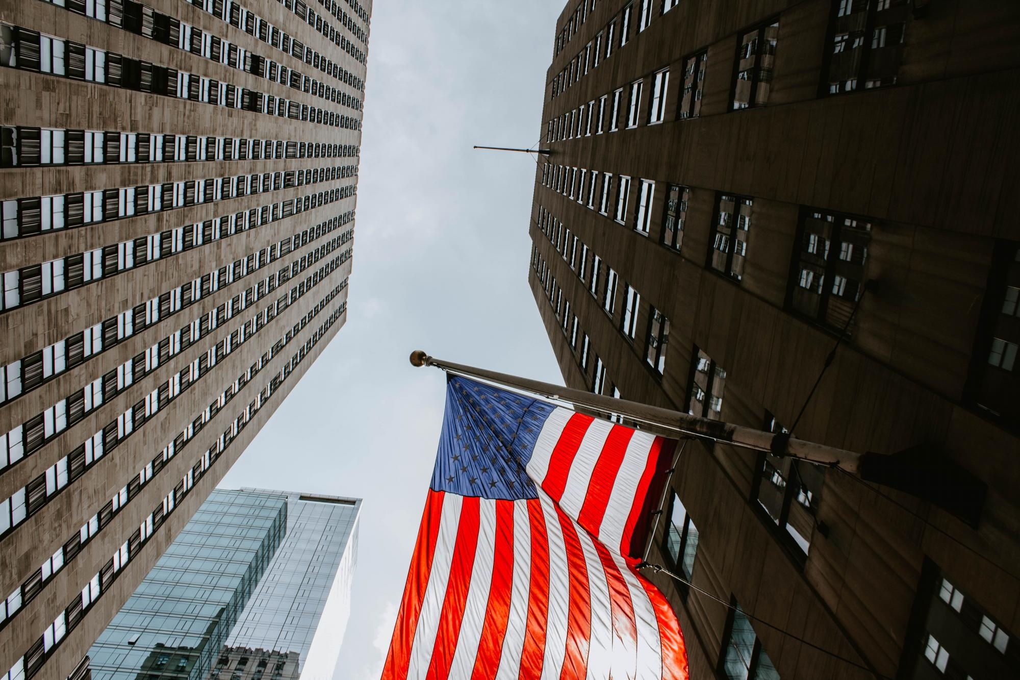 Bandera estadounidense ondeando en un edificio de Manhattan, NY (Freepick)