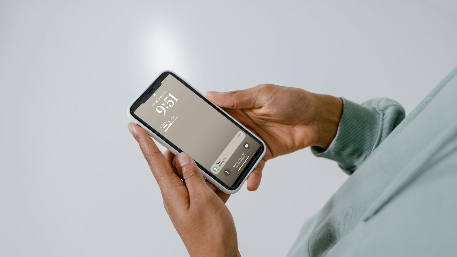 Hombre sosteniendo su celular con notificación de mensaje en WhatsApp. (Canva)