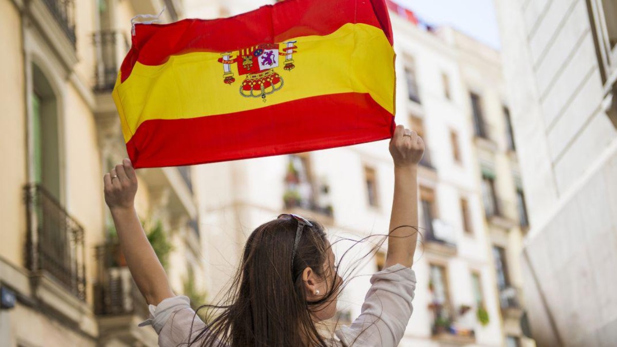 Imagen referencial de mujer sosteniéndo bandera de España. (Canva)