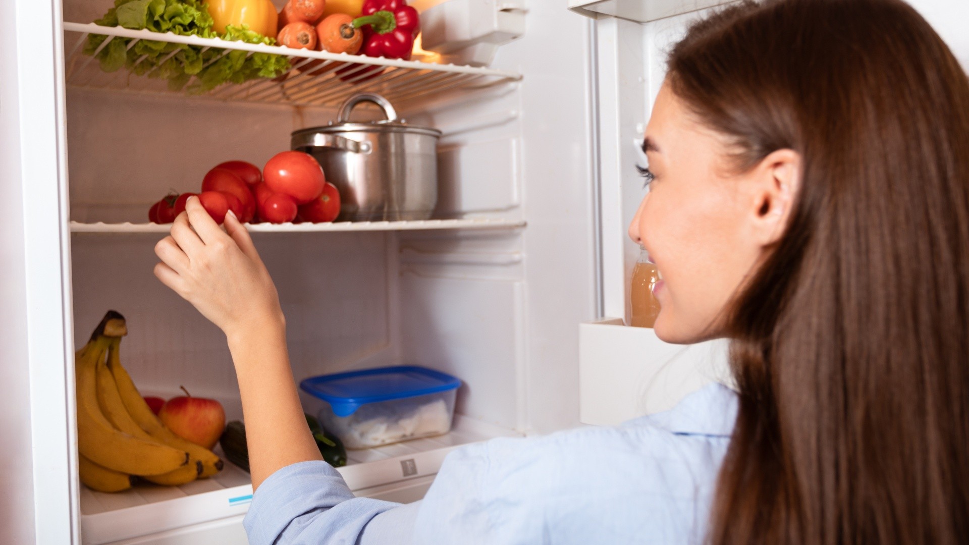 Mujer organizando su refrigerador (Canva)