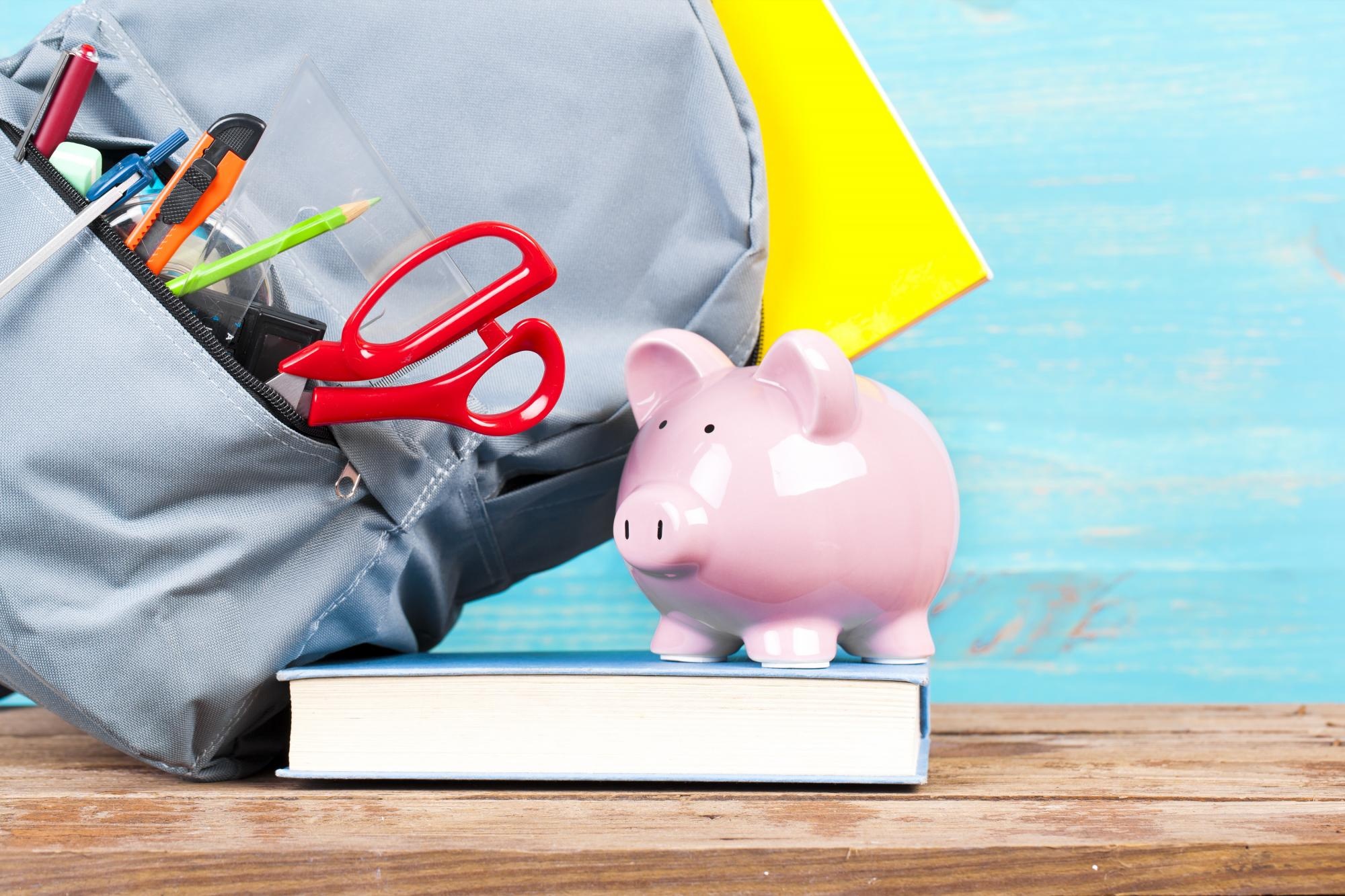 Imagen referencial de útiles escolares junto a una alcancía. (Cortesía)