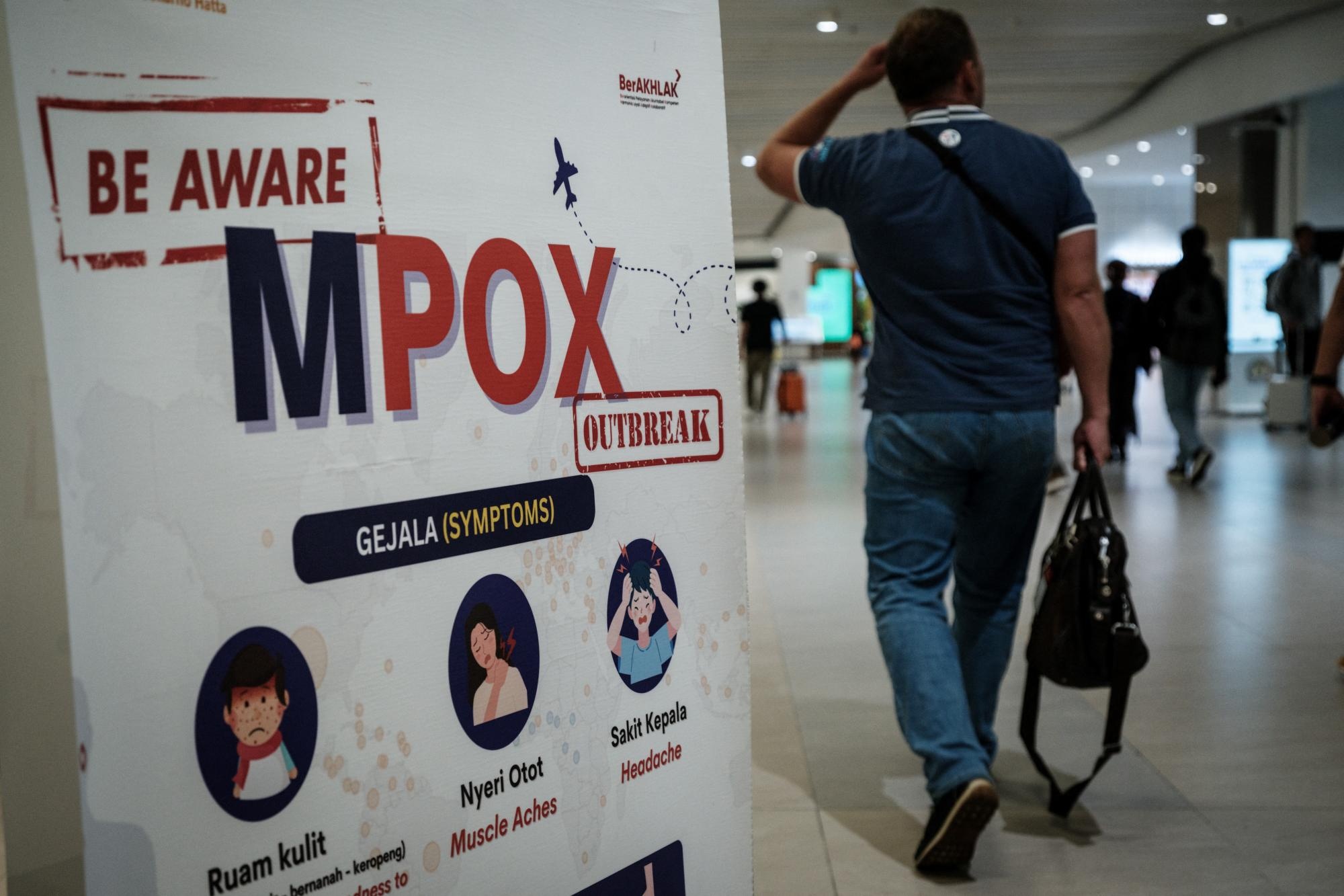 Un pasajero pasa junto a una pancarta que informa sobre la viruela del mono (MPOX) en el Aeropuerto Internacional Soekarno-Hatta en Tangerang. (AFP)