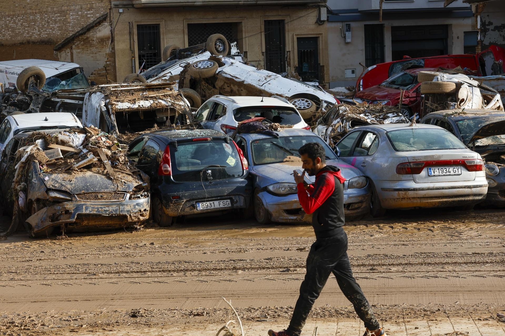 Un hombre camina junto a los coches apilados en Catarroja, Valencia, este martes, una de las localidades más afectados por las inundaciones. (Foto: EFE)