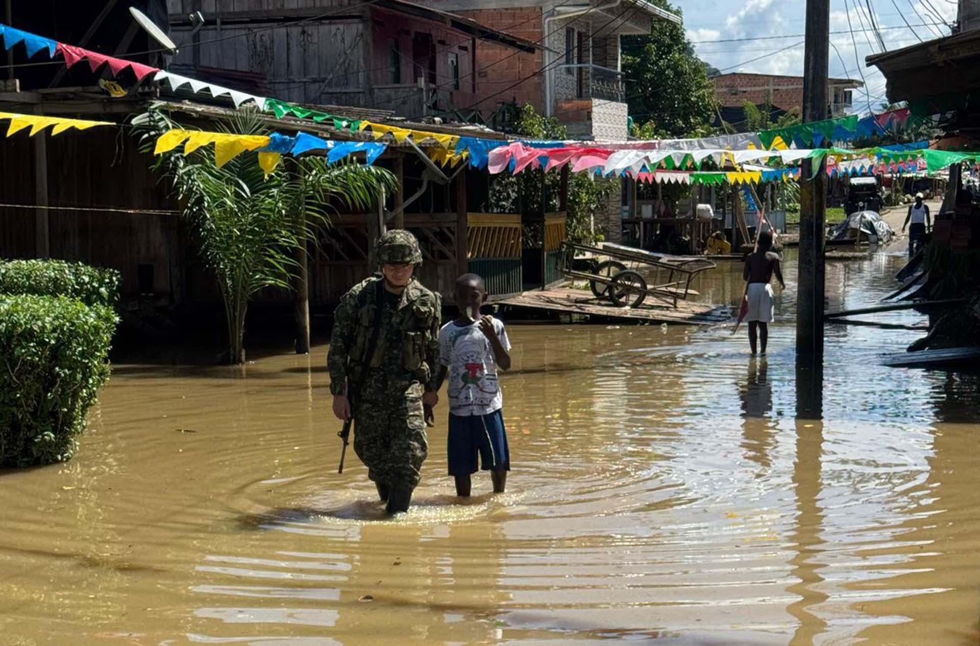 Un soldado acompañando a un joven por una calle inundada, en Alto Baudó (Colombia). (Ejército de Colombia / EFE)