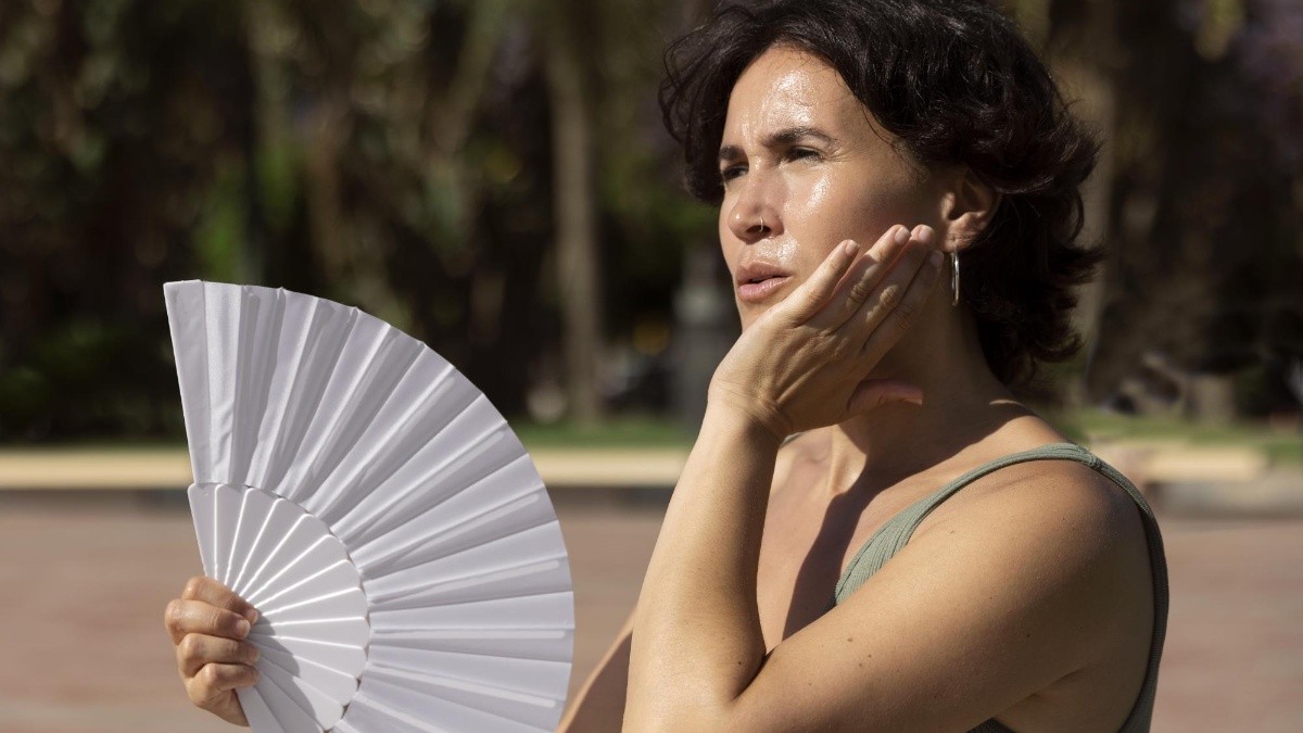 Mujer con un abanico con mucho calor. (FREEPIK)